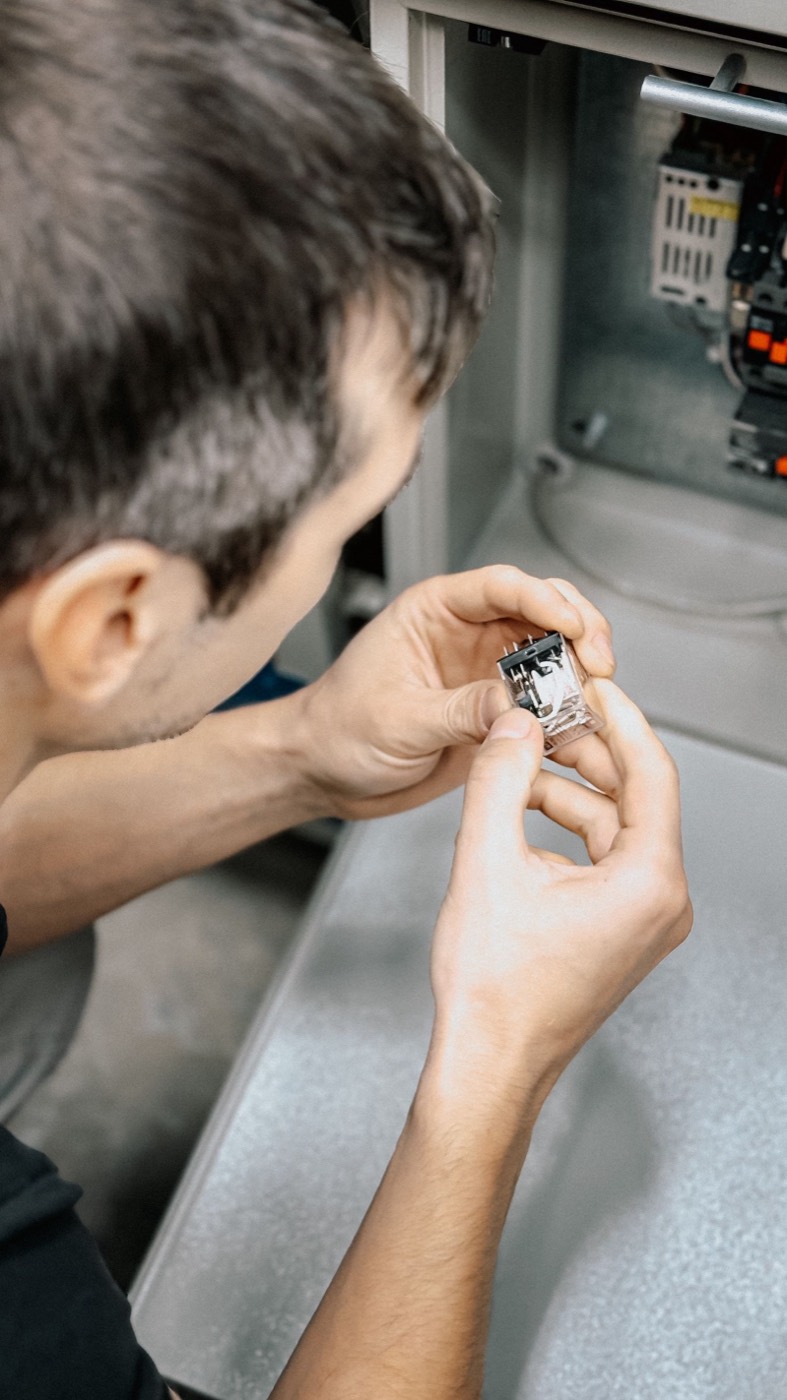 A maintenance technician inspecting an electrical component, representative of the Maintenance and Engineering department.